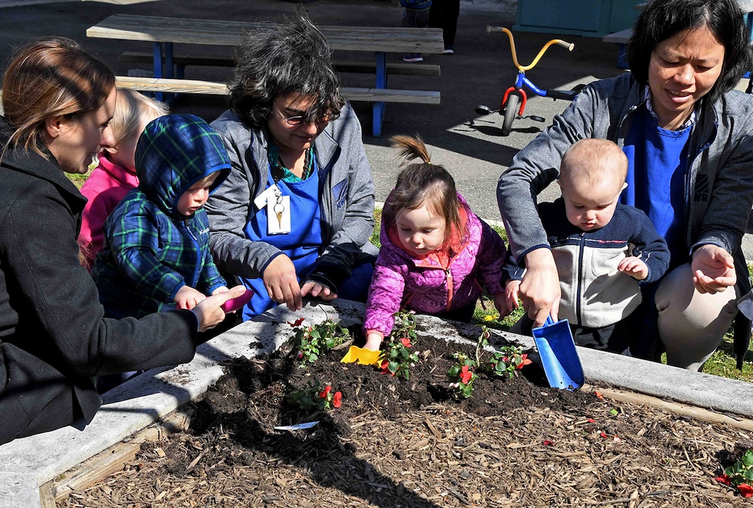 Child Development Center staff, parents and children plant flowers in honor of Earth Day in April 2018.