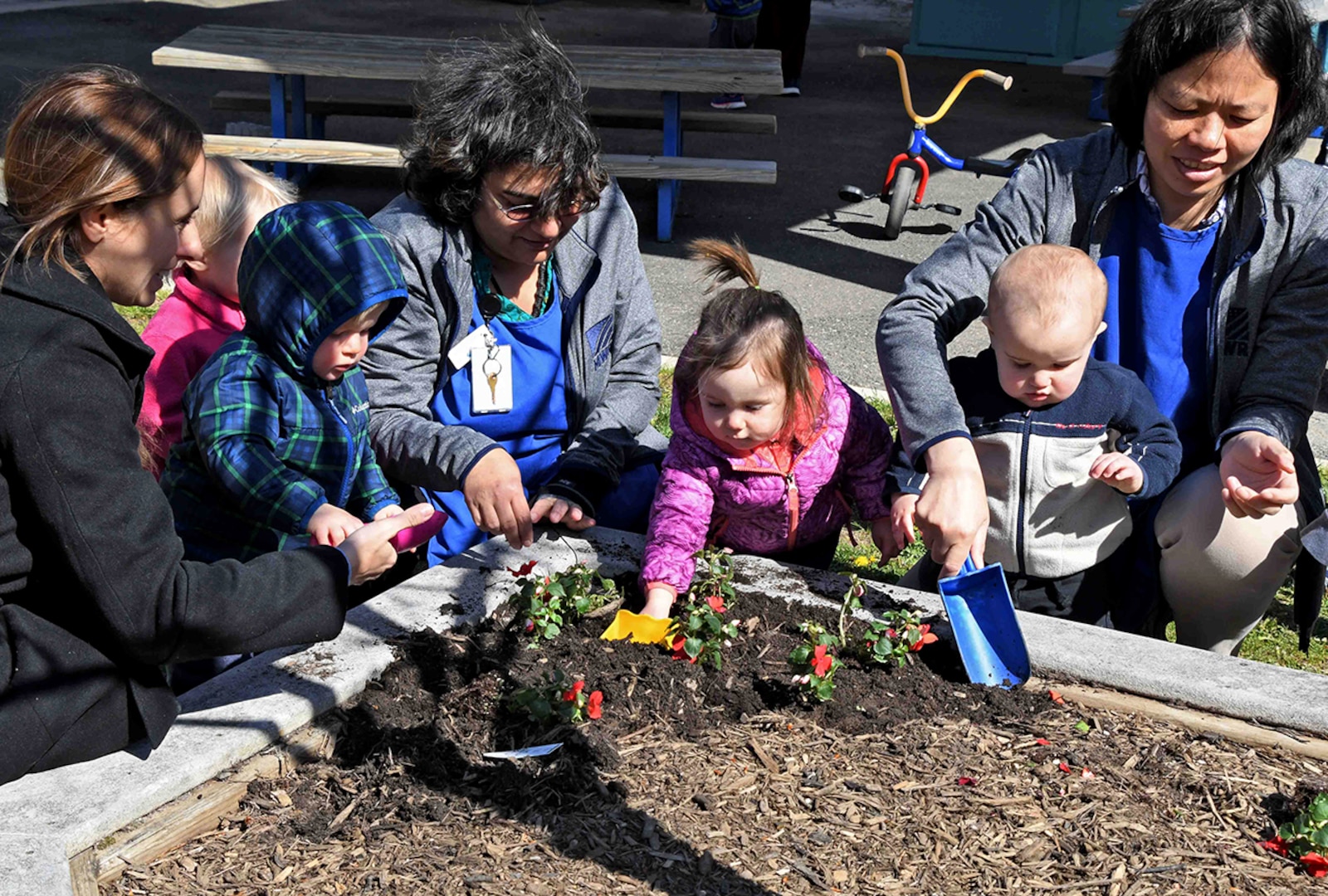 Child Development Center staff, parents and children plant flowers in honor of Earth Day in April 2018.