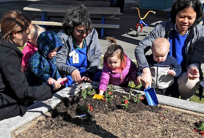 Child Development Center staff, parents and children plant flowers in honor of Earth Day in April 2018.