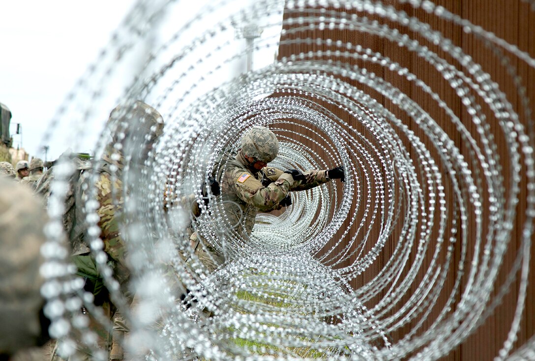 Army Pvt. William Crowder of the 887th Engineer Support Company applies concertina wire near Brownsville, Texas.