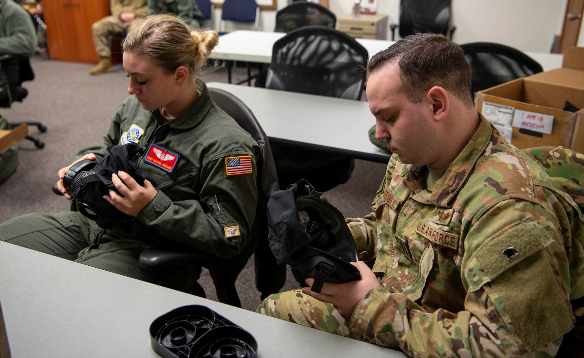 Capt. Alex Sewersky, 375th Aeromedical Evacuation Squadron flight nurse, and Staff Sgt. Rachel Melcher, 375th AES aeromedical evacuation technician, inspect the parts on their M50 gas masks during Chemical, Biological, Radiological and Nuclear training Feb. 7, 2019, at Scott Air Force Base, Illinois. During inspections, Airmen check for rotting, cracking, discoloration and fraying. The mask should be inspected every six months and every seven days during wartime or exercises. This ensures that the mask is serviceable and able to save the user’s life if needed. (U.S. Air Force photo by Airman 1st Class Miranda Simpson)