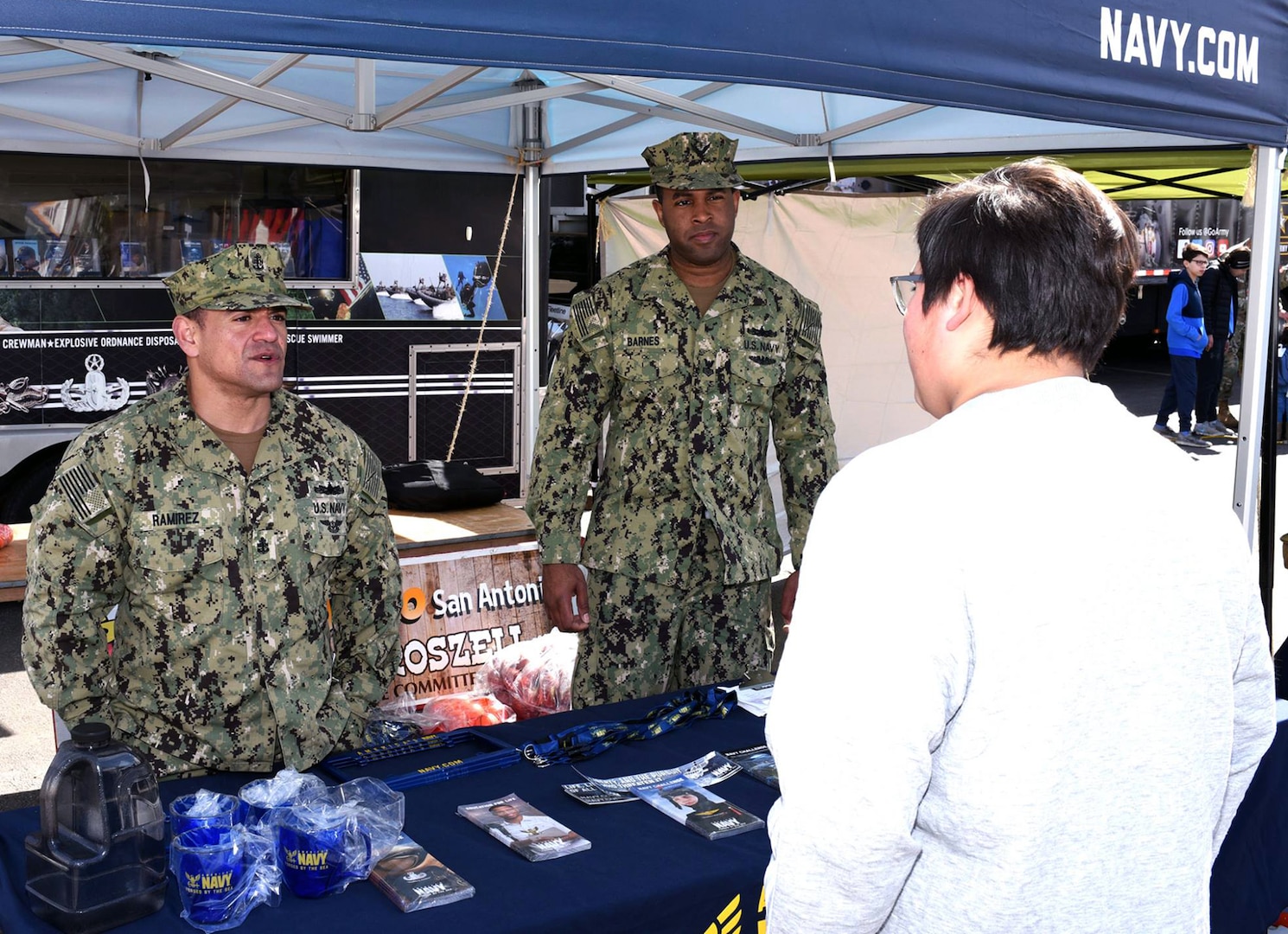 Chief Petty Officer Juan Ramirez (left) and Petty Officer 1st Class Vincent Barnes (right) of Navy Recruiting District San Antonio speak with an attendee at the San Antonio Stock Show and Rodeo.