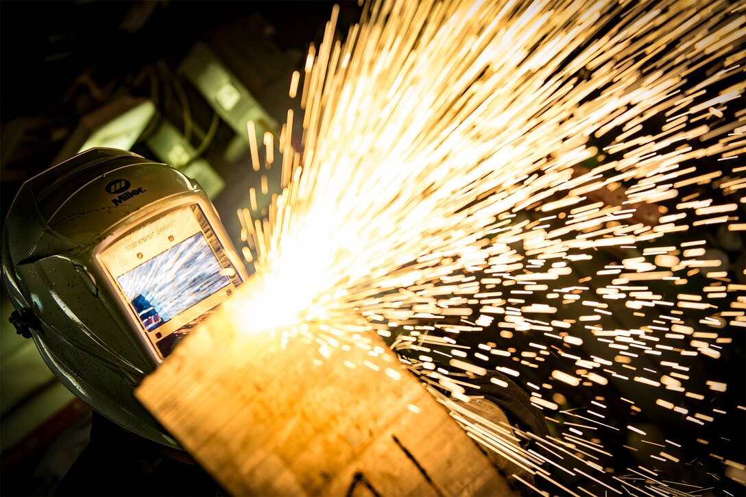 A service member cuts through metal with a plasma cutter.