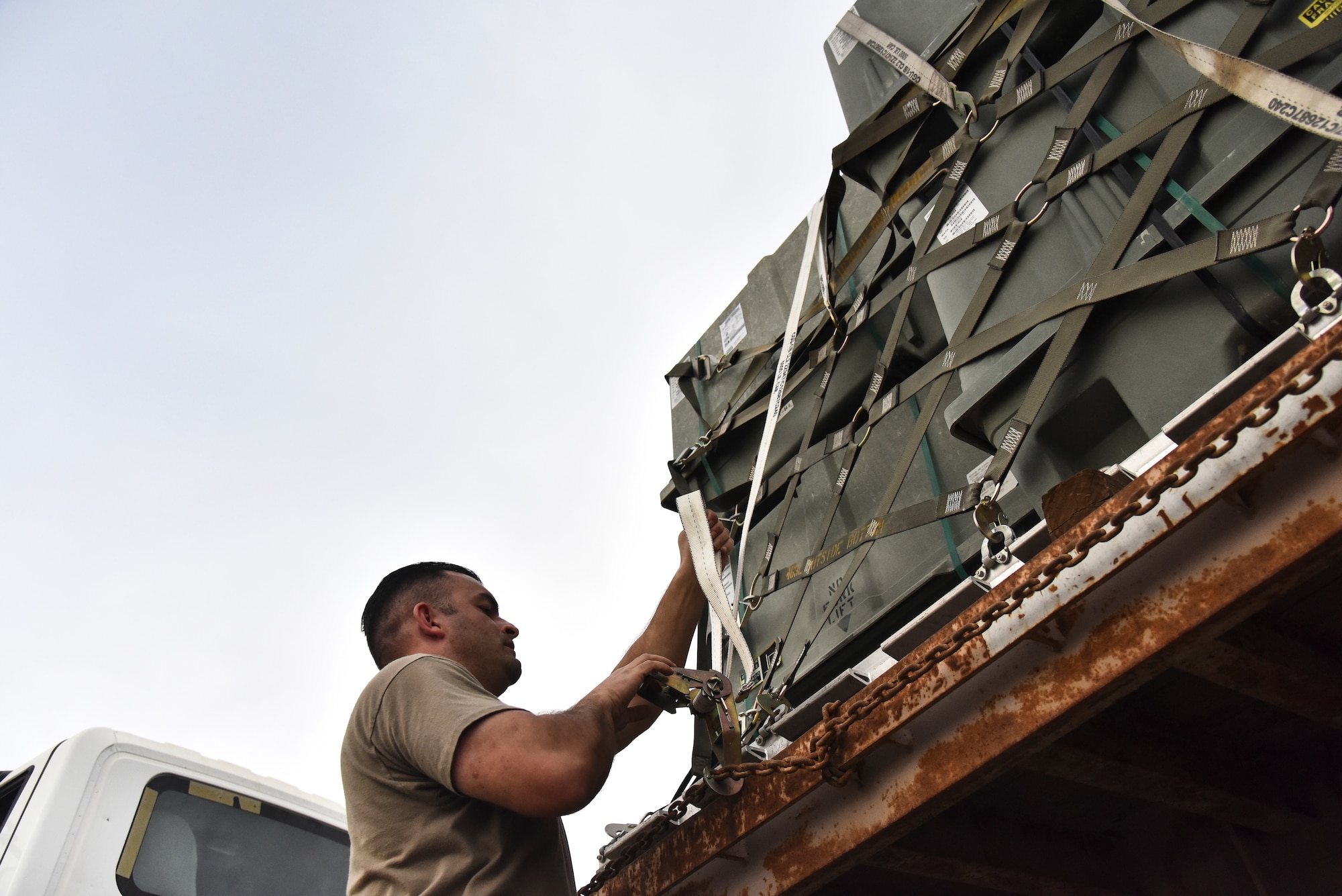 Tech. Sgt. Tyler Hawkins, 380th Expeditionary Maintenance Squadron munitions flight production section chief, secures the tie-down strap to a 40-foot trailer at Al Dhafra Air Base, United Arab Emirates, Feb. 15, 2019 Munitions Airmen receive, identify, inspect, store, recondition, ship, issue, deliver, maintain, test and assemble guided and unguided non-nuclear munitions. (U.S. Air Force photo by Senior Airman Mya M. Crosby)