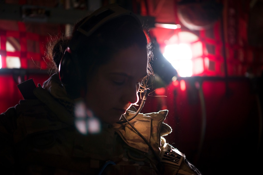 An airman looks down in a room with red walls.