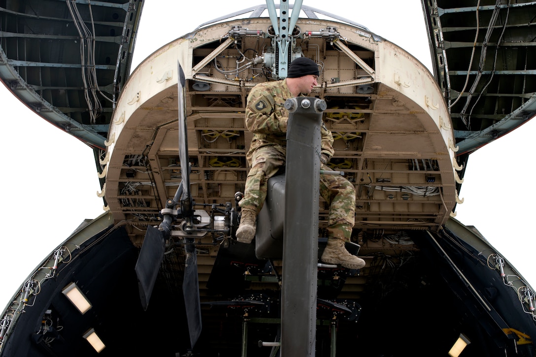 Airmen, Soldiers and personnel prepare to load Apache Helicopters into a C-5 Galaxy