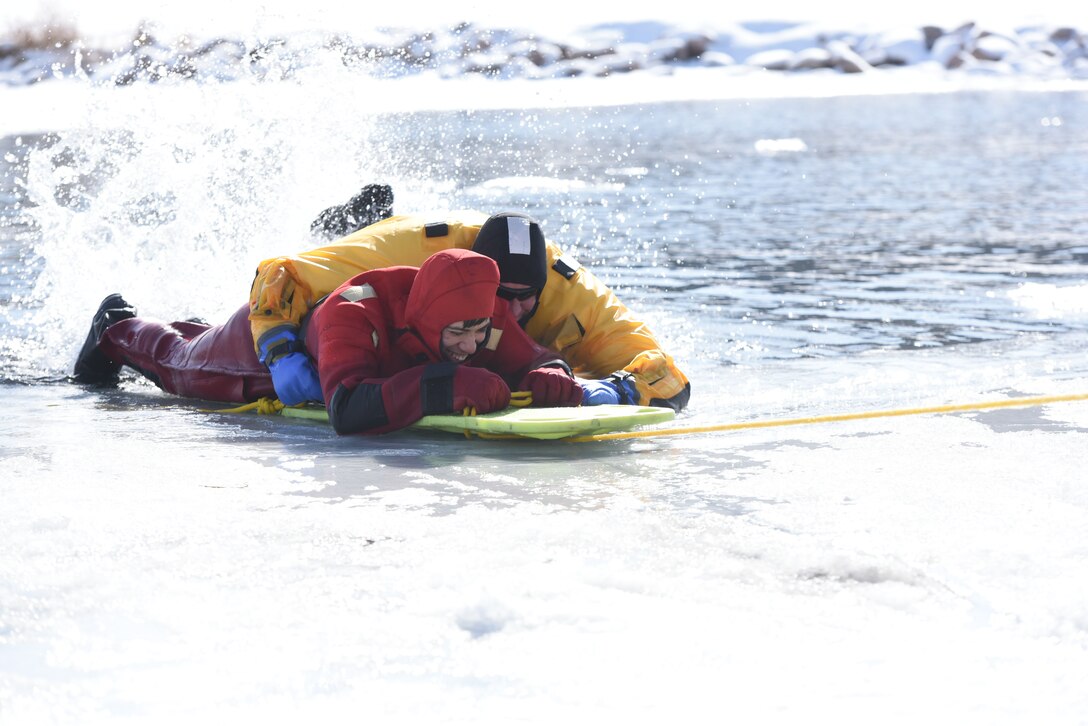 Airmen from the 28th Civil Engineer Squadron Fire Protection Flight take turns saving each other in the icy water at Canyon Lake in Rapid City, S.D., Feb. 12, 2019. This particular save required the rescuer to secure the patron to the boardbefore signaling the team to pull them out of the water. (U.S. Air Force photo by Senior Airman Michella Stowers)