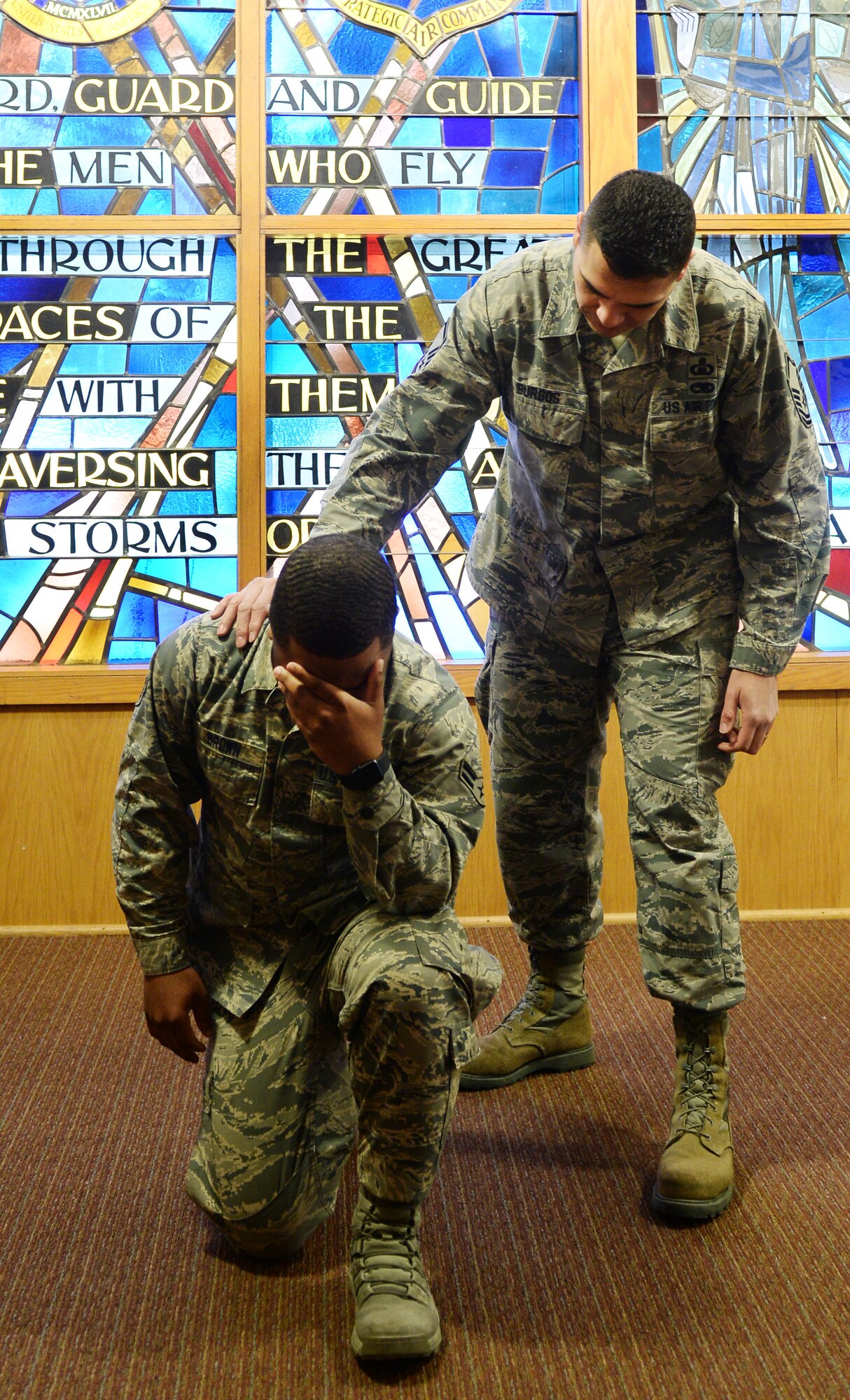 U.S. Air Force Airman 1st Class Dmarko Brown 55th Wing chaplain assistant, kneels down for a photo while U.S. Air Force Master Sgt. David Burgos, 55th Wing non-commission officer in charge chapel operations, places his hand on browns shoulder February 15, 2019, inside the Strategic Air Command Memorial chapel at Offutt Air Force Base, Nebraska.