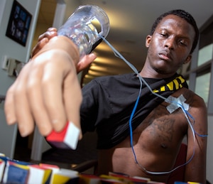 U.S. Army Staff Sgt. Kayshawn Porterfield practices picking up objects using a myoelectric prosthesis at Brooke Army Medical Center’s Center for the Intrepid at Joint Base San Antonio Fort Sam Houston Feb. 21. A myoelectric-controlled prosthesis is an externally powered artificial limb that the user controls with electrical signals generated naturally with his own muscles.