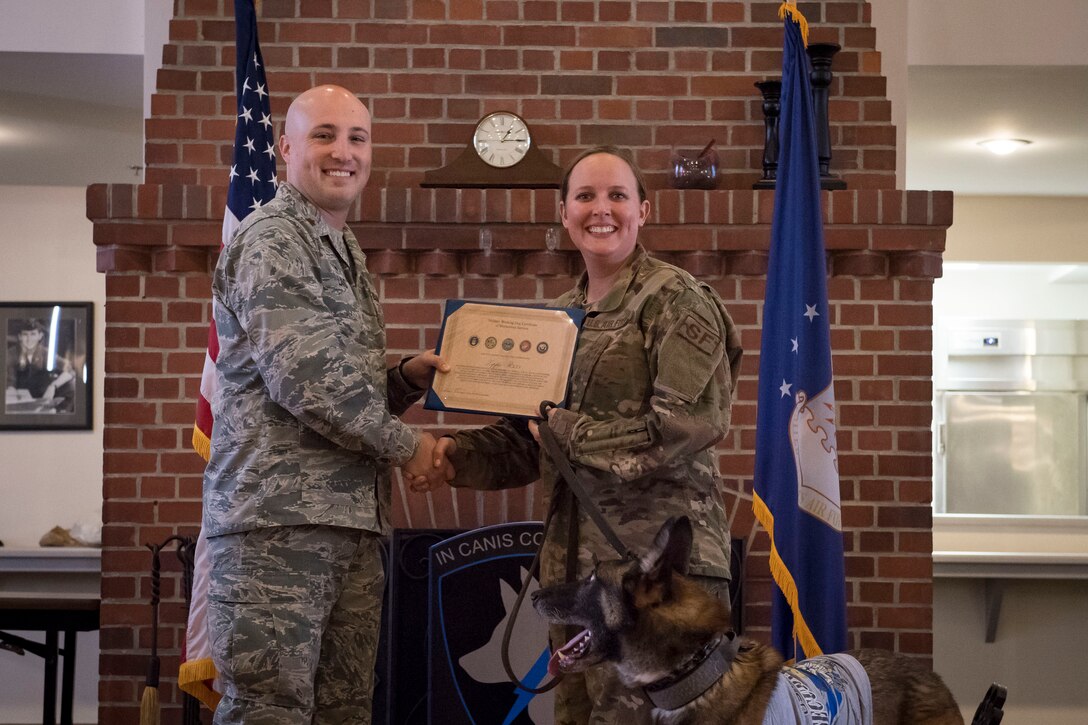 Maj. Daniel Land, 23d Security Forces Squadron (SFS) commander, poses for a photo with Staff Sgt. Lyndsay Gebhart, 23d SFS military working dog handler, after presenting military working dog ZIPPO with a Meritorious Service Award during a retirement ceremony, Feb. 21, 2019, at Moody Air Force Base, Ga. ZIPPO was assigned to the 325th Security Forces Squadron at Tyndall Air Force Base, Fl. in Nov. 2011, as a patrol/explosive dog. During his eight years on active duty, he’s deployed to Saudi Arabia twice and supported four United States Secret Service missions where he provided security for the President and Vice President of the United States. (U.S. Air Force photo by Senior Airman Janiqua P. Robinson)