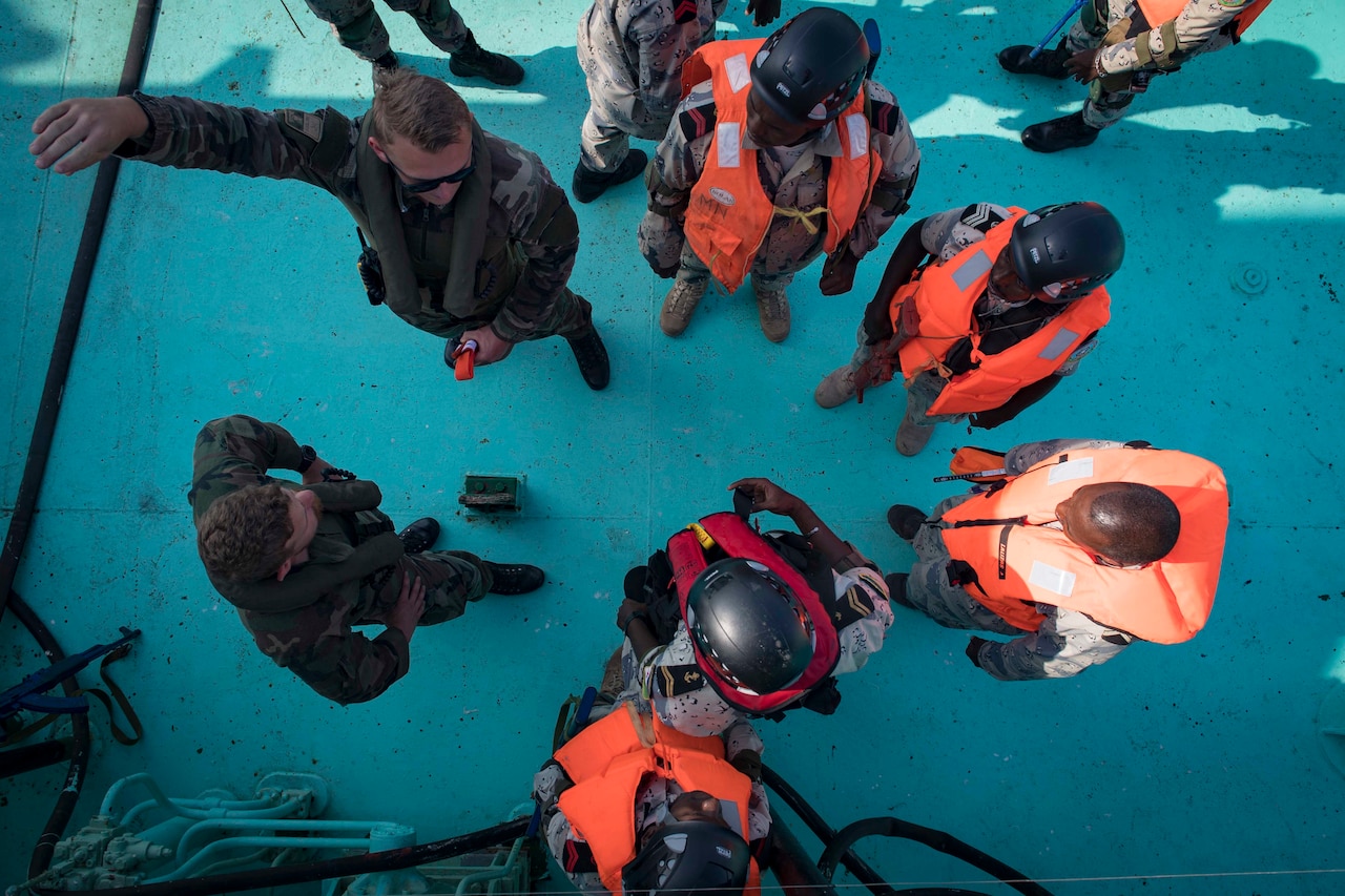 Sailors stand in a circle talking to each other.