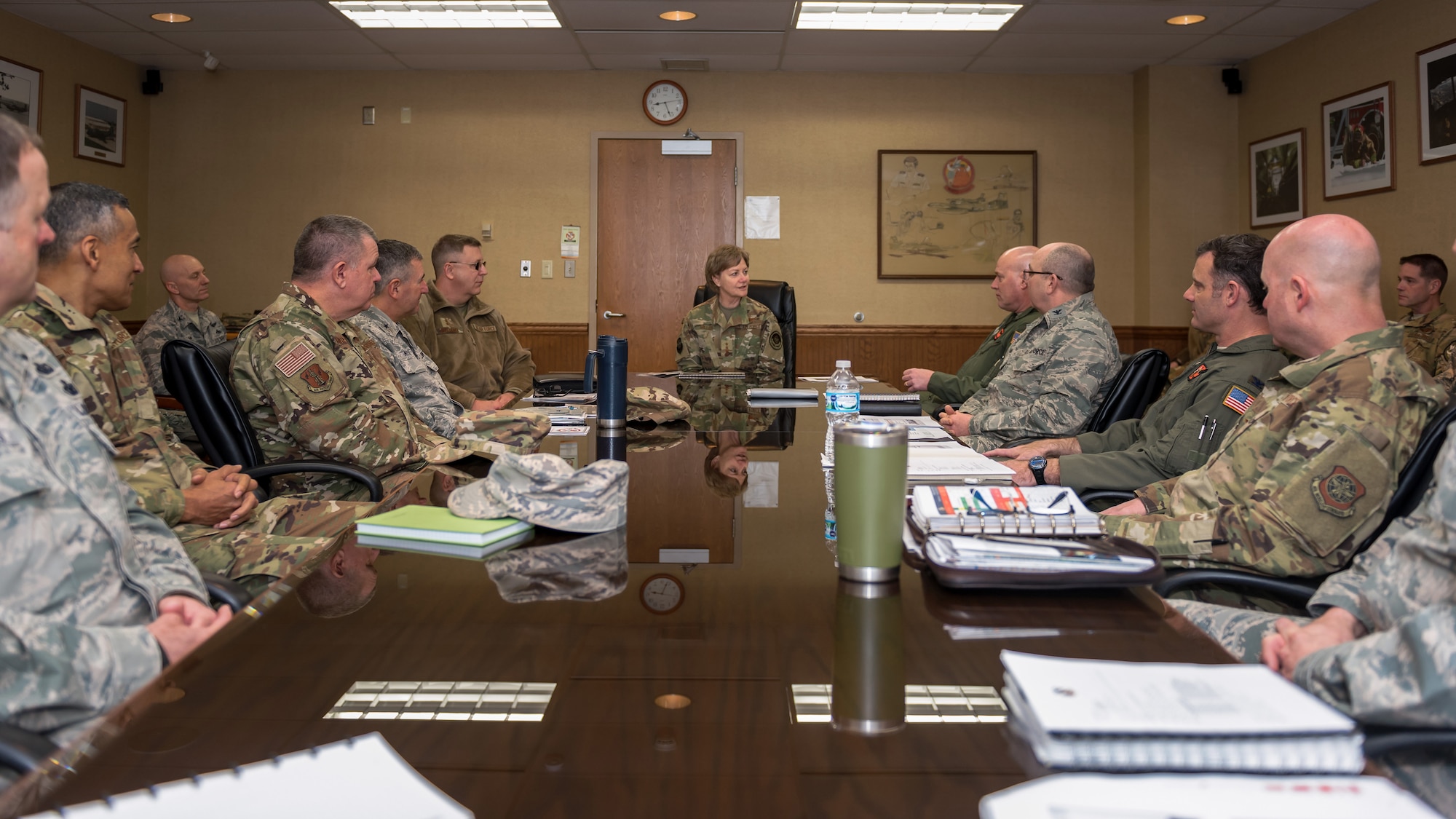 General talking with military members at table.