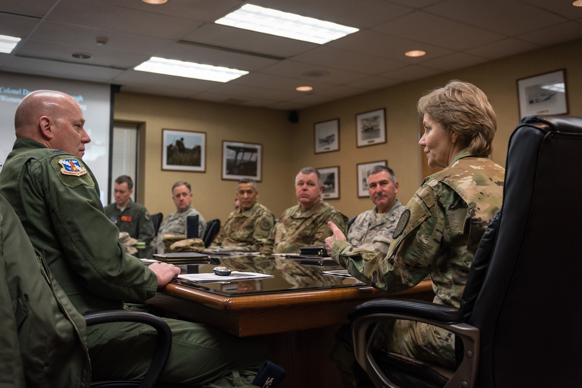 General talking with military members at table.