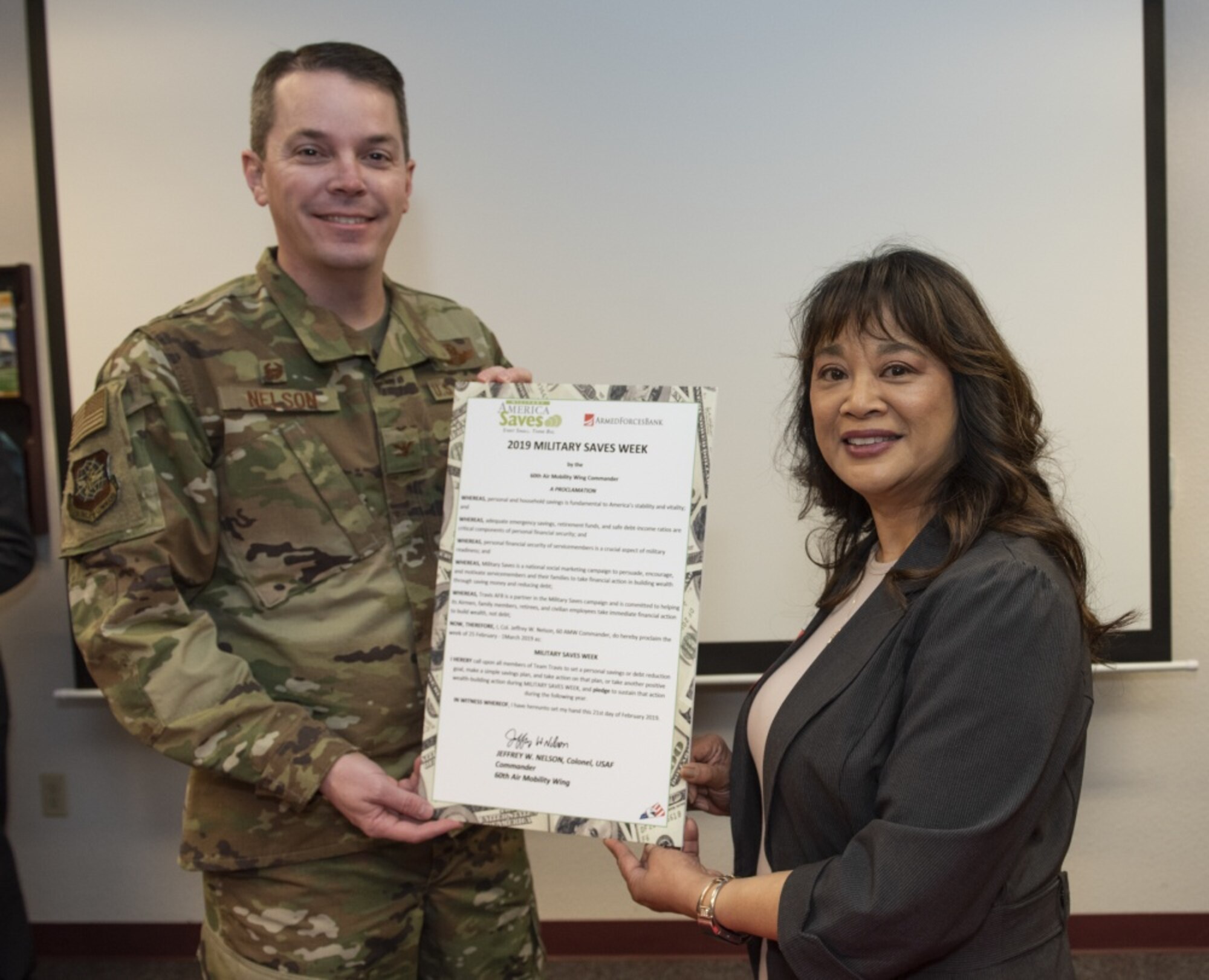 U.S. Air Force Col. Jeffrey Nelson, 60th Air Mobility Wing commander, and Marie Dollente, Armed Forces Bank, pose with a proclamation designating Feb. 25 through March 1, 2019 Military Saves Week at the Airman and Family Readiness Center, Feb. 21, 2019, Travis Air Force Base, California. The Military Saves Week program encourages Airman to save for the future and to reduce debt. The event is a team effort between the A&FRC, Travis Credit Union and Armed Forces Bank. (U.S. Air Force Photo by Heide Couch)