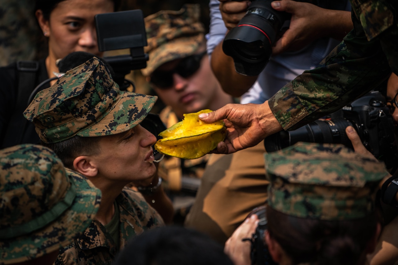 A Marine takes a bit of  star fruit during jungle training.