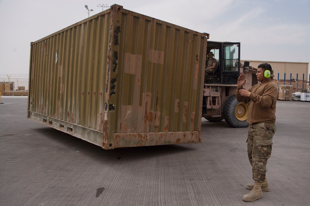 Airman Dylan Durham, 379th Expeditionary Logistics Readiness Squadron (ELRS) traffic management office (TMO) traffic management apprentice, acts as a ground guide Senior Airman Nicholas Mote, 379th ELRS TMO traffic management journeyman, while moving a shipping container Feb. 22, 2019, at Al Udeid Air Base, Qatar. The 379th ELRS TMO handles the pick-up, storage, shipment, and delivery of assets such as small vehicle parts, aircraft engines, and clothing items throughout the U.S. Central Command area of responsibility. (U.S. Air Force photo by Tech. Sgt. Christopher Hubenthal)