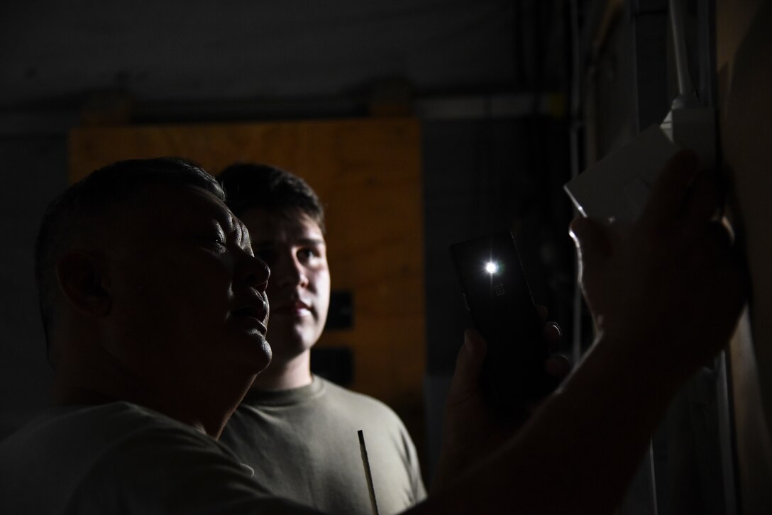 Senior Airmen  Michael Young and Zachary Ford, 380th Expeditionary Civil Engineer Squadron electrical systems journeymen, troubleshoot a light switch at Al Dhafra Air Base, United Arab Emirates, Feb. 18, 2019. Electrical systems specialists troubleshoot malfunctions using technical orders, manufacturers' handbooks, local procedures, codes, and directives.  (U.S. Air Force photo by Senior Airman Mya M. Crosby)