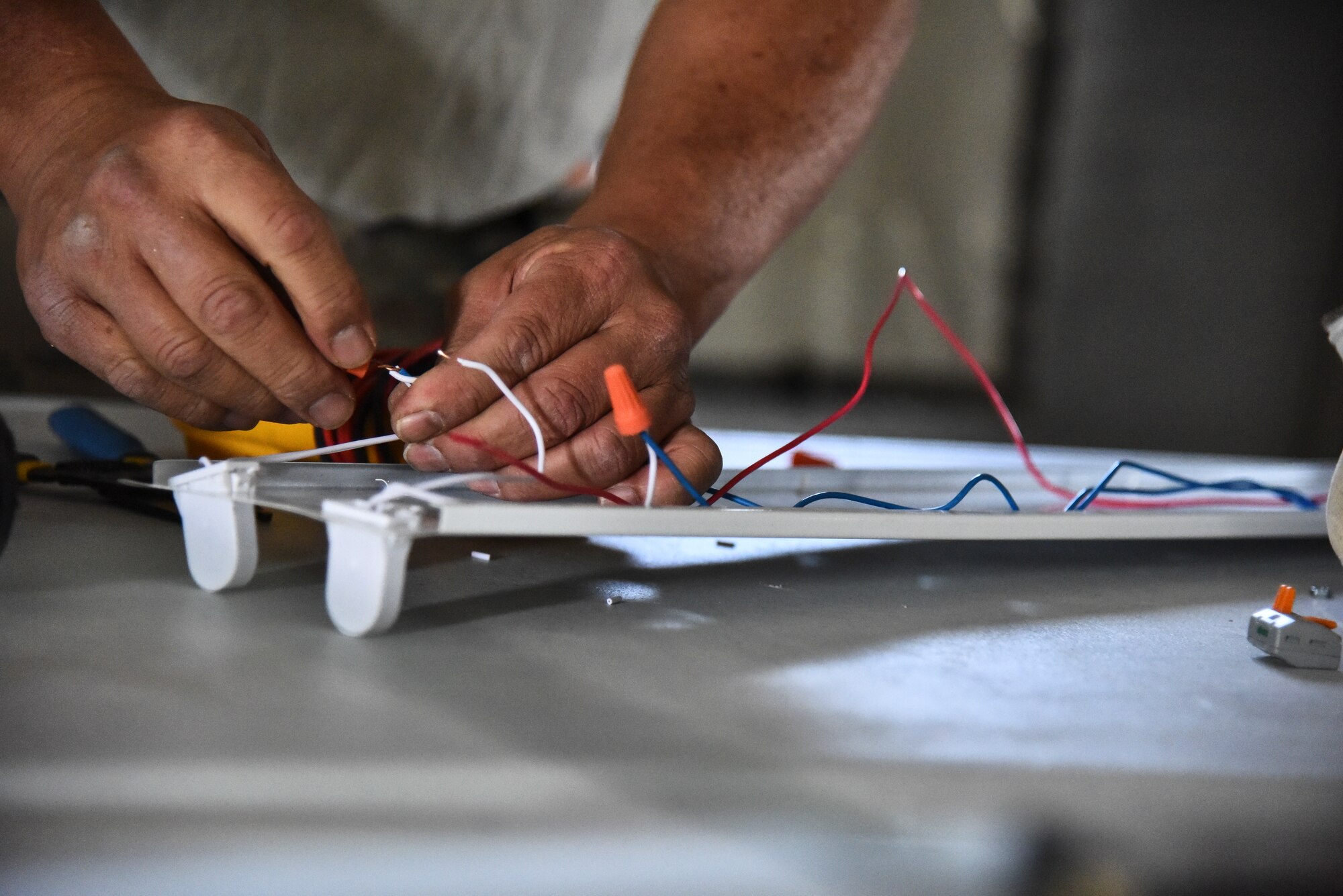 Senior Airman Michael Young, 380th Expeditionary Civil Engineer Squadron electrical systems journeyman, wire a ballast at Al Dhafra Air Base, United Arab Emirates, Feb. 18, 2019. Electrical systems specialists troubleshoot malfunctions using technical orders, manufacturers' handbooks, local procedures, codes, and directives.  (U.S. Air Force photo by Senior Airman Mya M. Crosby)