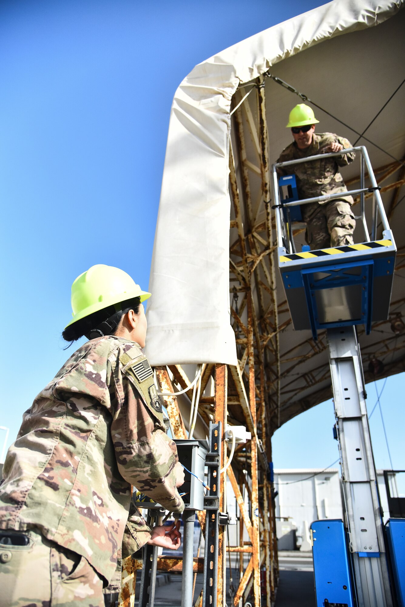 Staff Sgt. Joseph Walters, 380th Expeditionary Civil Engineer Squadron electrical systems craftsman, speaks to Senior Airman Angelica Gutierrez, 380th ECES electrical systems journeyman, at Al Dhafra Air Base, United Arab Emirates, Feb. 18, 2019. Electrical systems specialists are trained to climb utility poles and operate special purpose vehicles and equipment, including line maintenance and high reach trucks to inspect, maintain and repair overhead distribution systems. (U.S. Air Force photo by Senior Airman Mya M. Crosby)