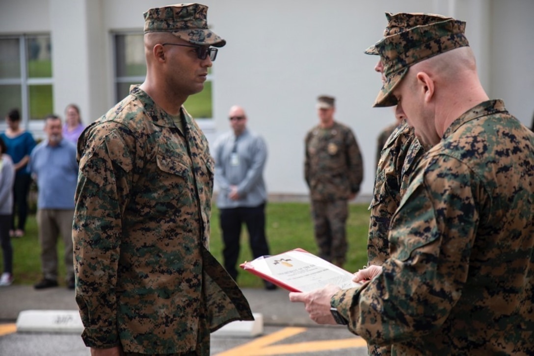 First Sergeant Jacob Karl, right, reads Staff Sgt. Jonathan McClure’s, left, Navy Achievement Medal citation February 22, 2019, at Camp Foster, Okinawa, Japan. McClure was awarded the NAM for superior performance of duty while serving as a military policeman and accident investigation section chief Provost Marshal’s office, H&S Bn, MCIPAC-MCB. With quick thinking and a bias for action, McClure rescued a woman from choking at a local restaurant.