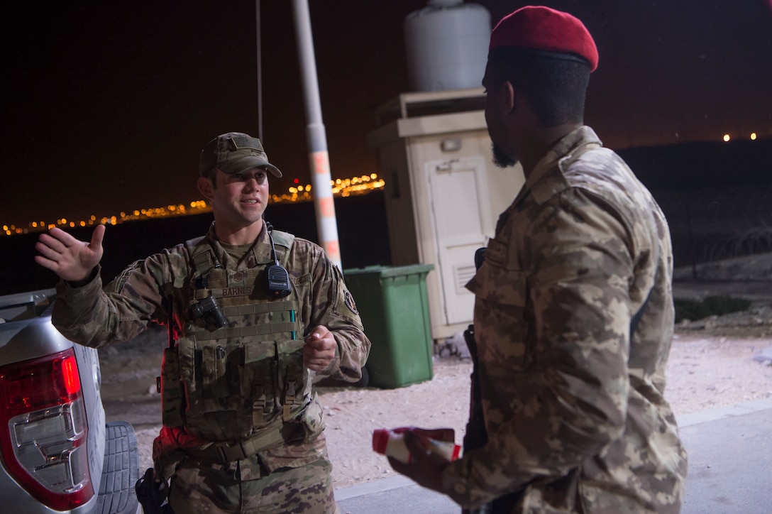 Master Sgt. Jordan Barnes, center, 379th Expeditionary Security Forces Squadron (ESFS) combined response joint patrol leader, talks to a member of the Qatar Military Police (QMP), during a “Spartan Patrol” Jan. 17, 2019, at Al Udeid Air Base, Qatar. Barnes works side-by-side with the QMP to conduct the patrols, which check for vulnerabilities in the installation’s perimeter. Barnes aims to perform one patrol a night to provide security and build the partnership between U.S. Air Force and Qatar Armed Forces.  (U.S. Air Force photo by Tech. Sgt. Christopher Hubenthal)