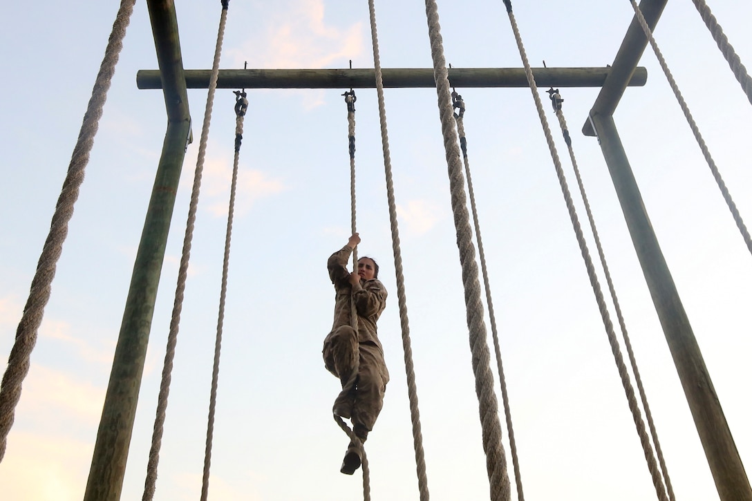 A Marine Corps recruit climbs a rope.