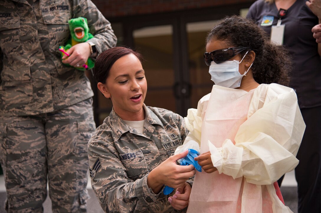 Senior Airman Shinique Manders, 23d Aeromedical Dental Squadron, helps a child dress like a dentist during a visit to the Child Development Center, Feb. 22, 2019, at Moody Air Force Base, Ga. Members of the dental clinic spoke with children from the Child Development Center about the importance of dental hygiene for National Children's Dental Health Month. (U.S. Air Force Photo by Andrea Jenkins)