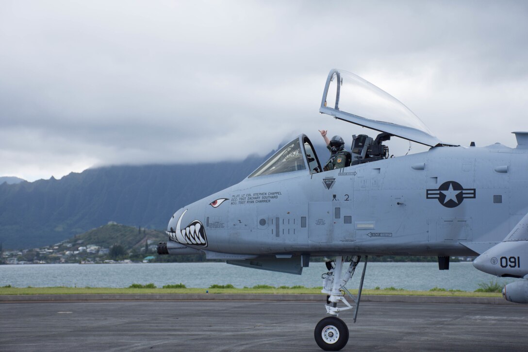 A service member signals from an aircraft.