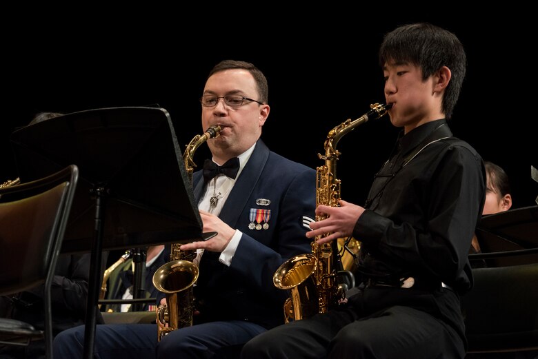 A member of the USAF Band of the Pacific plays alongside a member of the Hamura Daiichi Jr. High School Band during the Japan-U.S. Joint Concert Feb. 24, 2019, at the Hamura Learning Center in Hamura, Tokyo, Japan. Members of the USAF Band of the Pacific and the Hamura Daiichi Jr. High School Band mixed and played as one for the event. (U.S. Air Force photo by Senior Airman Donald Hudson)