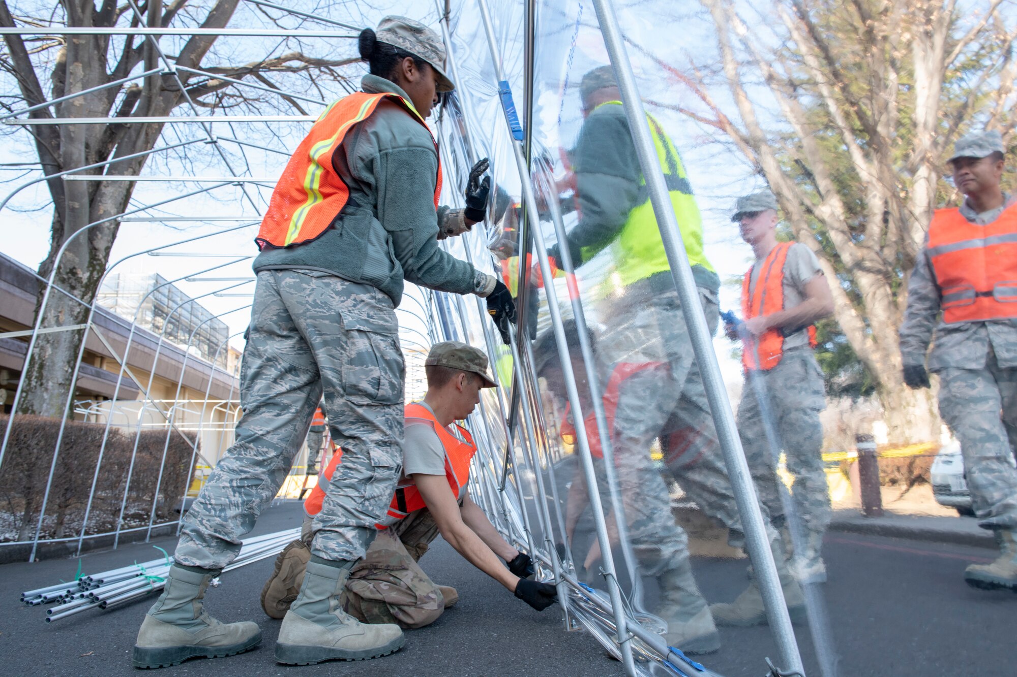 Airmen from the 374th Civil Engineer Squadron work together to secure the weather-resistant coating of a temporary corridor at Yokota Air Base, Japan, Feb. 21, 2019.