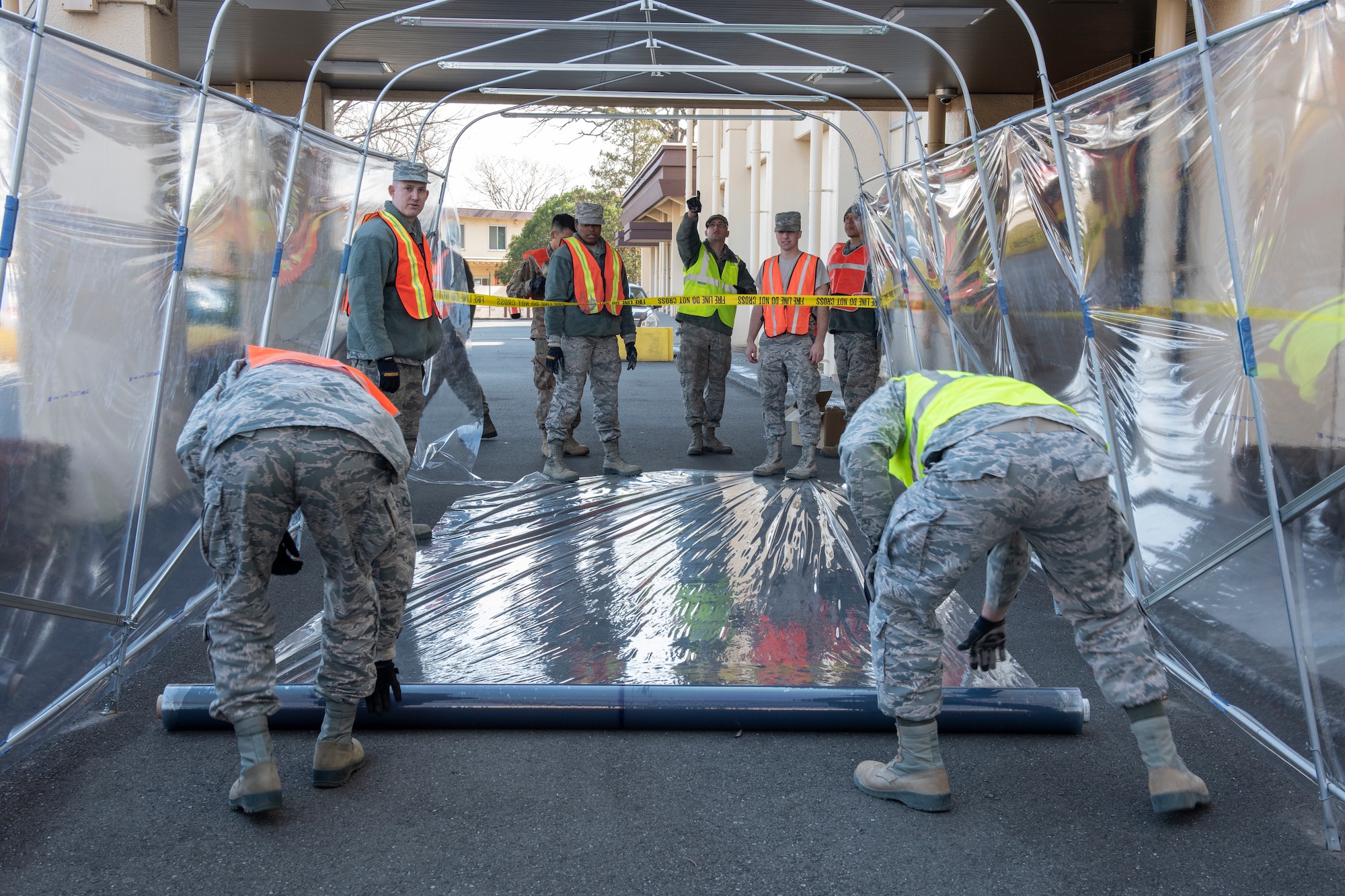 Airmen from the 374th Civil Engineer Squadron measure the weather-resistant material prior to installing the roof of a temporary corridor at Yokota Air Base, Japan, Feb. 21, 2019.
