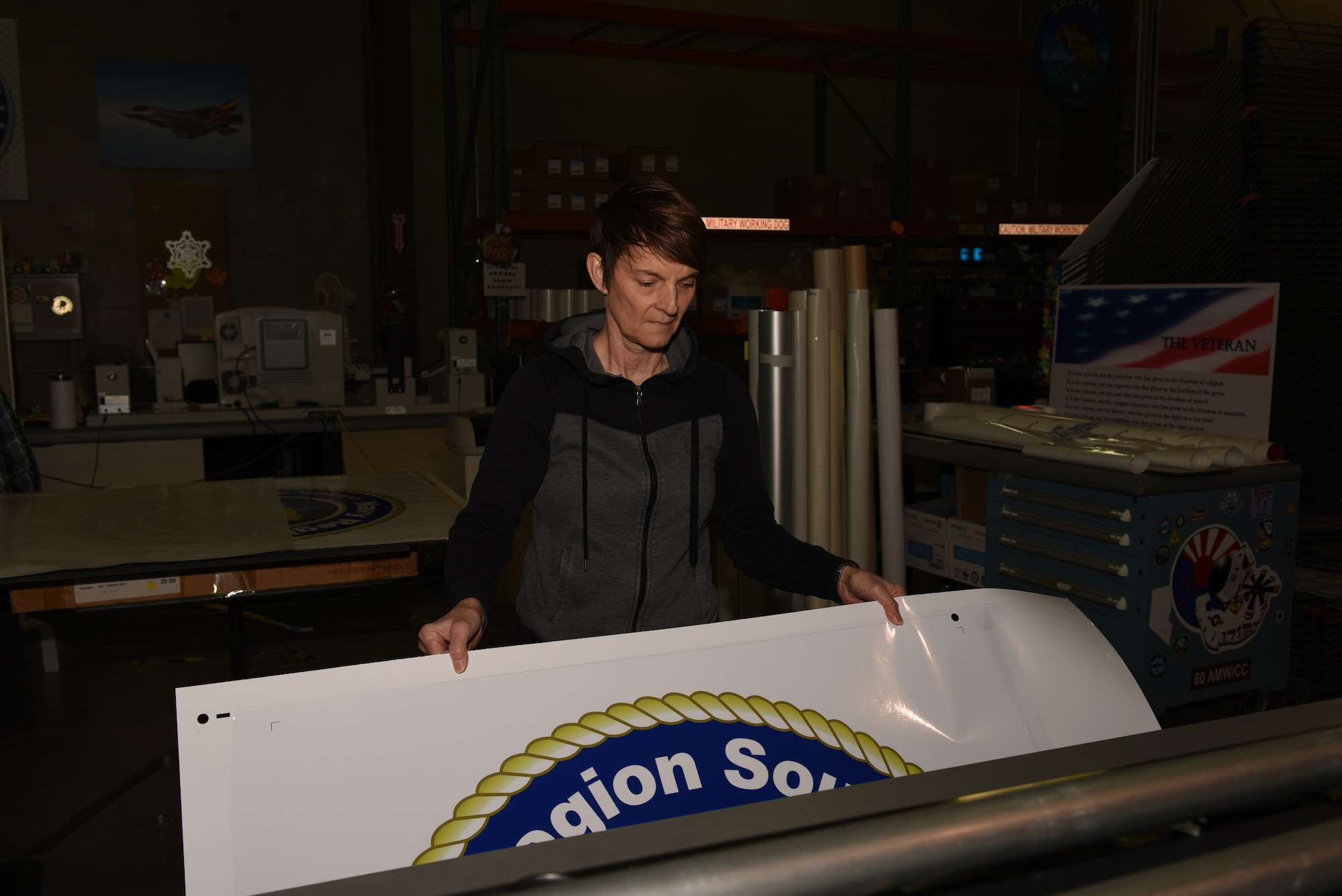 Kathy Kruczek, Defense Logistics Agency Document Automation Production specialist, prepares to cut out large U.S. Navy decals Feb. 7, 2019, at Travis Air Force Base, Calif. Kurczek has worked for DLA full-time since 2008 and has worked at Travis since 1993. The Travus DLA facility provides a variety of printing services to federal agencies and government offices. (U.S. Air Force photo by Tech. Sgt. James Hodgman)