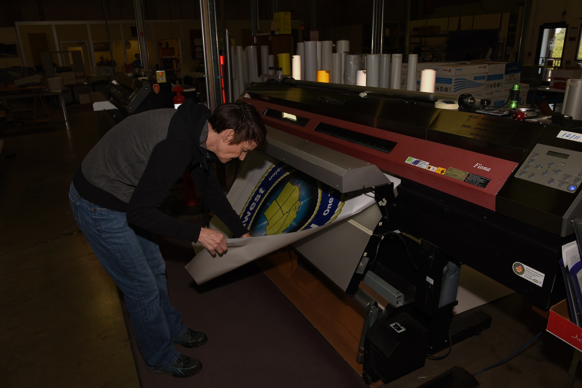 Kathy Kruczek, Defense Logistics Agency Document Automation Production specialist, prepares to cut out large U.S. Navy decals Feb. 7, 2019, at Travis Air Force Base, Calif. Kurczek has worked for DLA full-time since 2008 and has worked at Travis since 1993. DLA provides a variety of printing services to federal agencies and government offices. (U.S. Air Force photo by Tech. Sgt. James Hodgman)