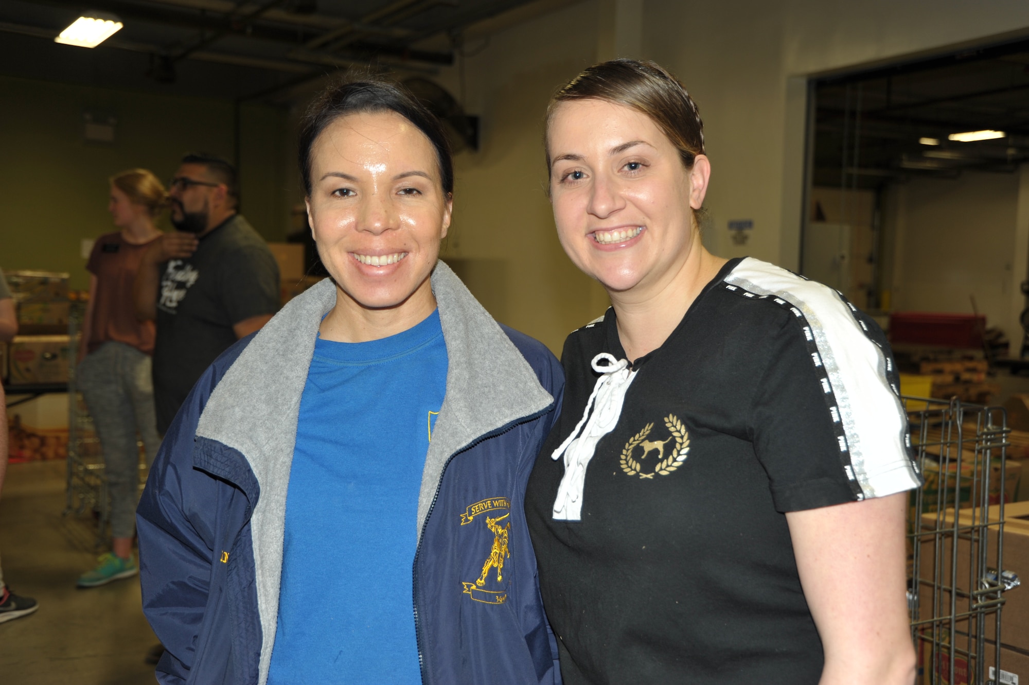 Master Sgt. Angelina Manby (left) and Tech. Sgt. Kassandra Farani pose for a pic at the end of the 340th FTG’s Feb. 22 community outreach event in support of the San Antonio Foodbank. Manby and Farani organized the event, during which the 340th team and fellow volunteers sorted and packed more than 10,000 pounds of food and non-food items, including pet supplies. (U.S. Air Force photo by Debbie Gildea)