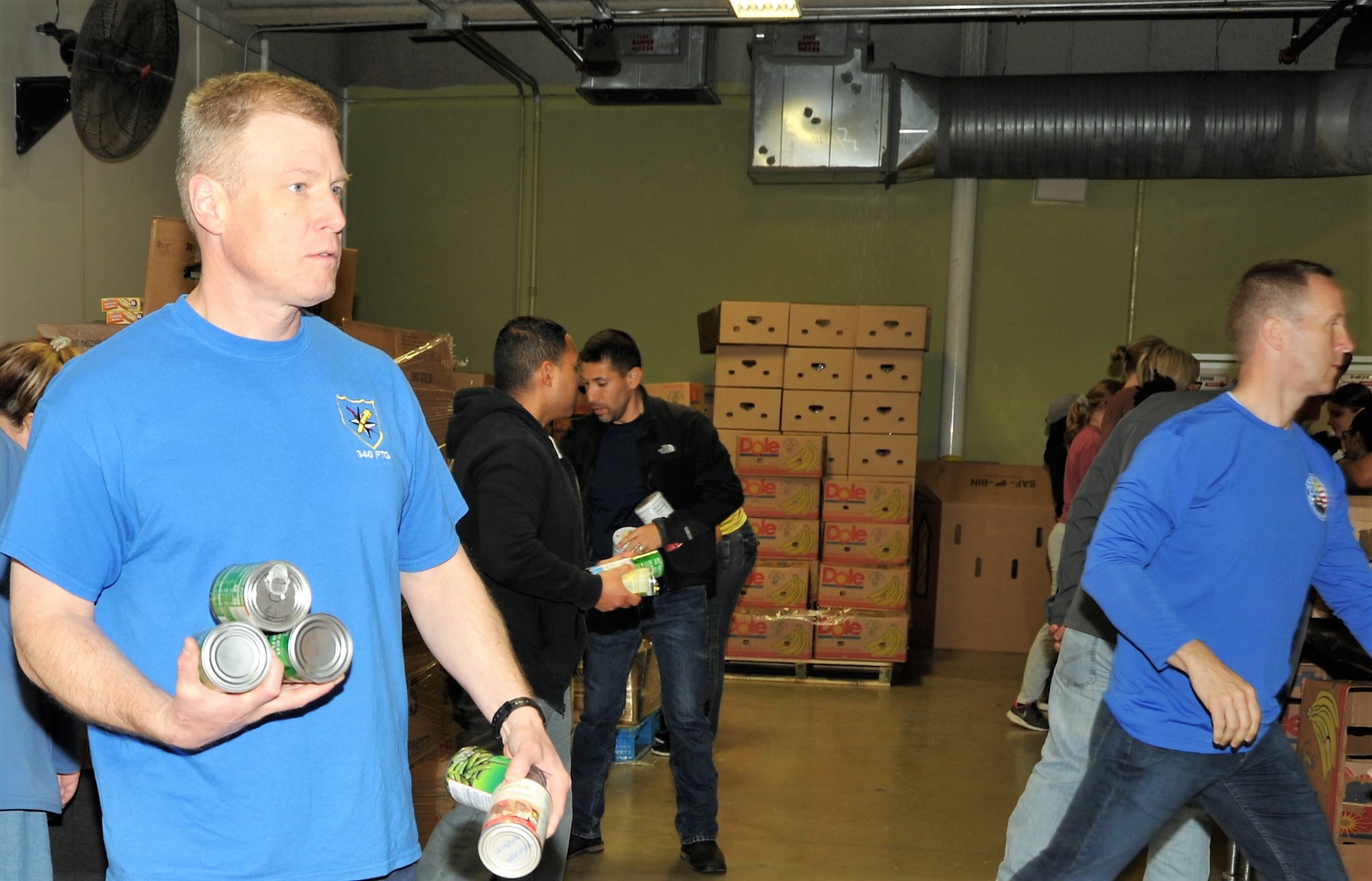 Col. Allen Duckworth, 340th FTG Commander, takes loose cans of food to the appropriate packing stations while group superintendent Chief Master Sgt. Scott Goetze works to keep debris and boxes out of packers’ way during the 340th FTG’s Feb. 22 community outreach event in support of the San Antonio Foodbank. Together, the 340th team and fellow volunteers sorted and packed more than 10,000 pounds of food. (U.S. Air Force photo by Debbie Gildea)