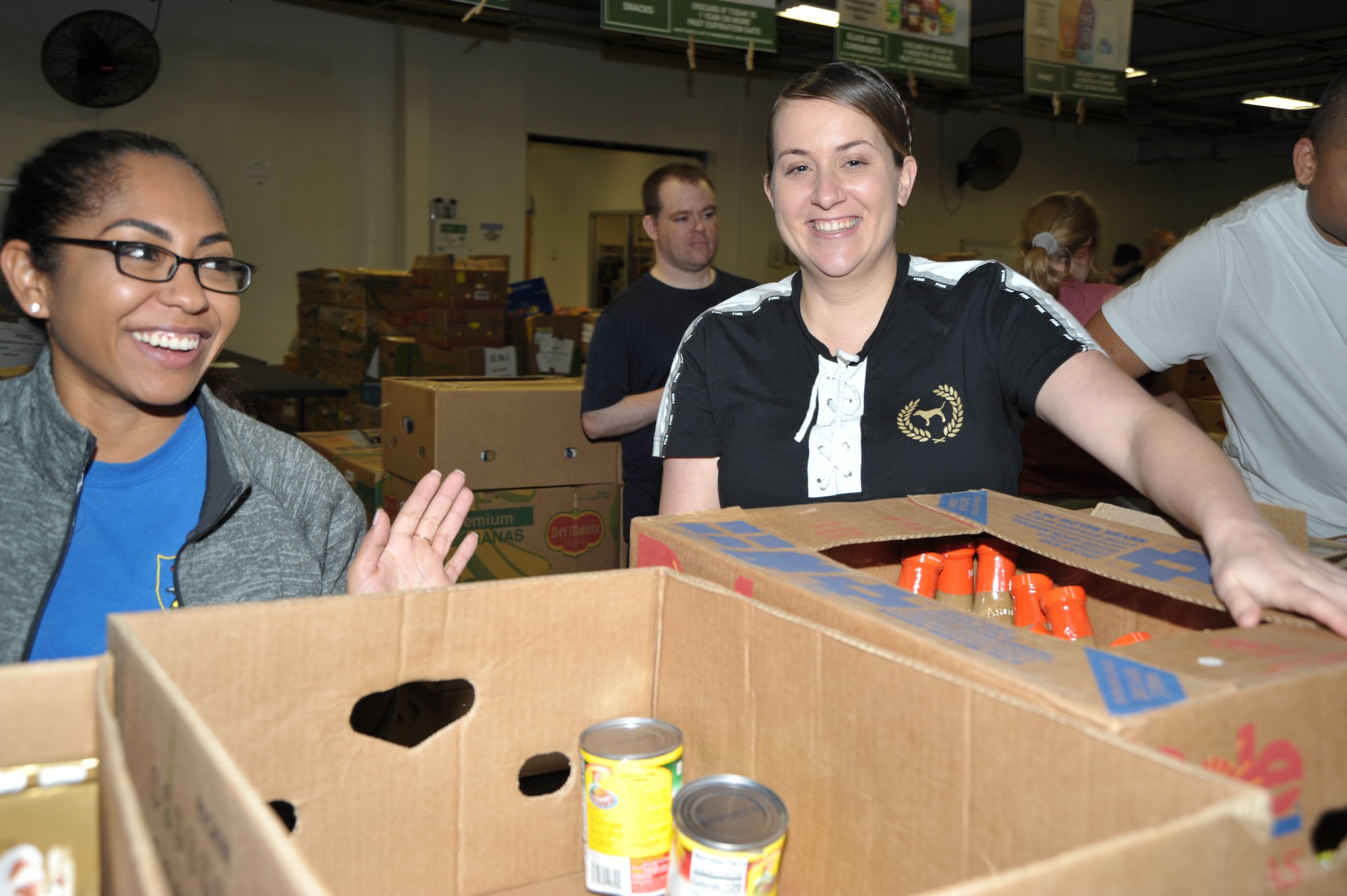 Master Sgt. Natasha Todd and Tech. Sgt. Kassandra Farani share a fun moment while sorting and packing food during the 340th FTG’s Feb. 22 community outreach event in support of the San Antonio Foodbank. Together, the 340th team and fellow volunteers sorted and packed more than 10,000 pounds of food. (U.S. Air Force photo by Debbie Gildea)