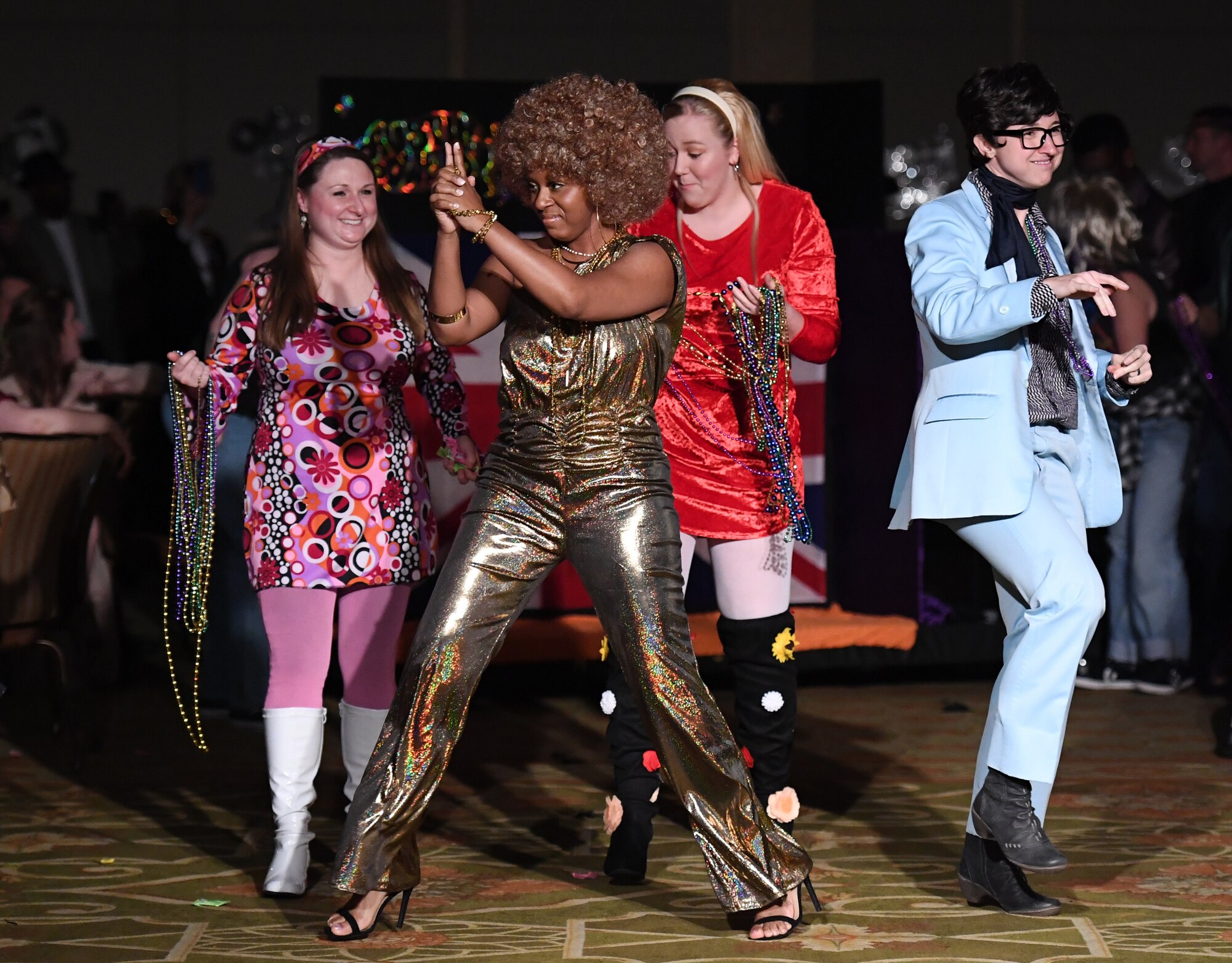 Members of the 81st Medical Operations Squadron portray the Austin Powers cast as they make their way down the aisle during the 31st Annual Krewe of Medics Mardi Gras Ball at the Bay Breeze Event Center on Keesler Air Force Base, Mississippi, Feb. 23, 2019. The Krewe of Medics hosts a yearly ball to give Keesler Medical Center personnel a taste of the Gulf Coast and an opportunity to experience a traditional Mardi Gras, which is celebrated by the local communities. The theme for this year's ball was Hollywood vs. Broadway. (U.S. Air Force photo by Kemberly Groue)