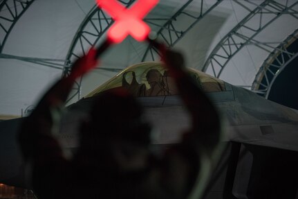 U.S. Air Force Airman 1st Class Alan Bernal, 1st Aircraft Maintenance Squadron assistant dedicated crew chief, guides an F-22 Raptor pilot under a sunshade at Joint Base Langley-Eustis, Virginia, Feb. 21, 2018.