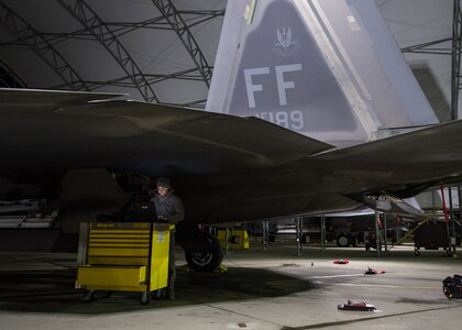 U.S. Air Force Airman 1st Class Alan Bernal, 1st Aircraft Maintenance Squadron assistant dedicated crew chief, checks technical orders under the wing of an F-22 Raptor at Joint Base Langley-Eustis, Virginia, Feb. 21, 2018.