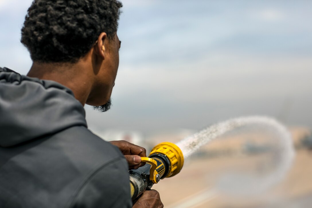 Travis Feeney, outside linebacker for the San Diego Fleet football team, sprays the hose of a P-19 firetruck during a tour at Marine Corps Air Station Miramar, Calif., Feb. 26. The San Diego Fleet football team visited MCAS Miramar to further foster cohesion between the San Diego community and MCAS Miramar. (U.S. Marine Corps photo by Sgt. Jake McClung)