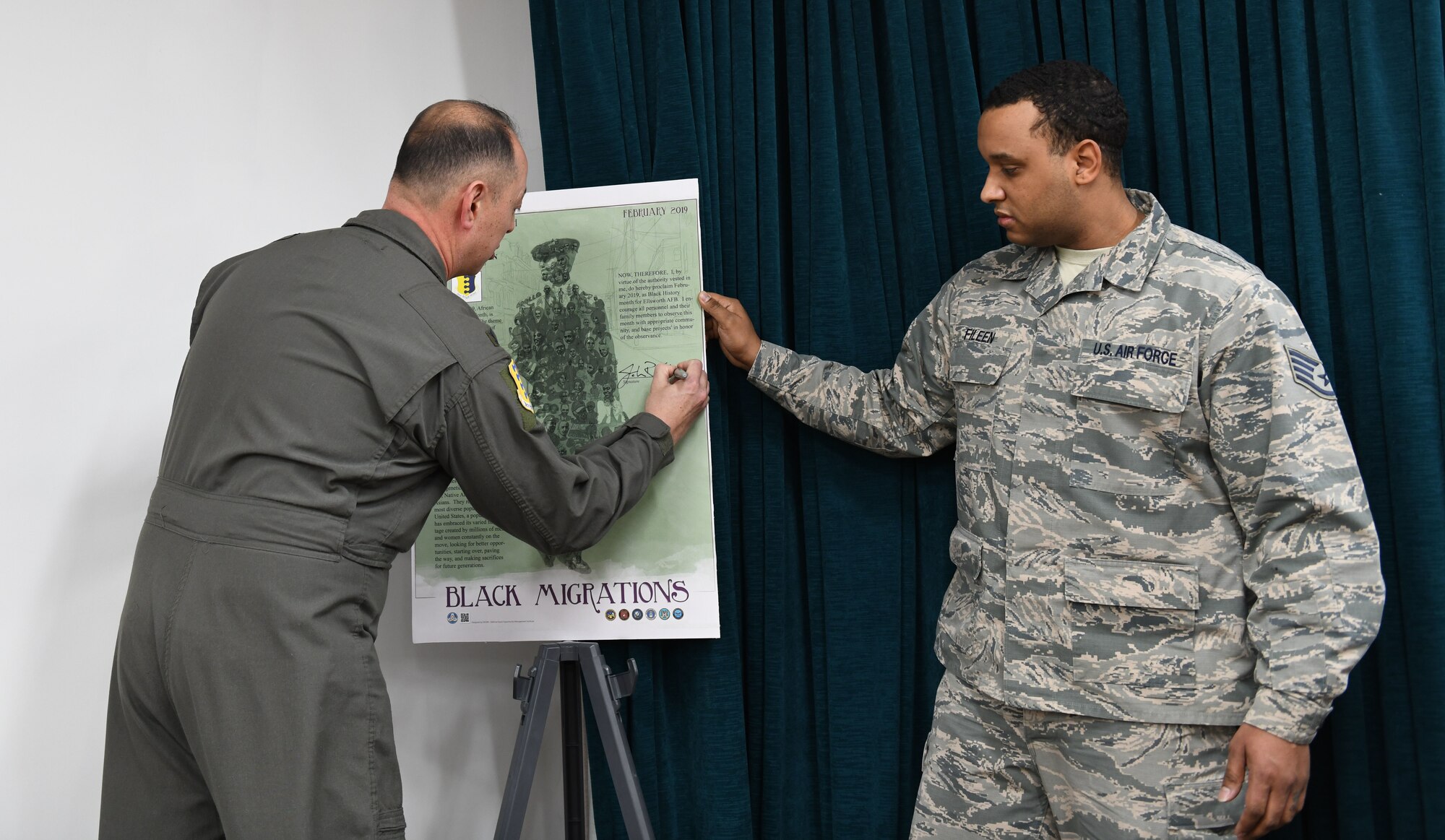 Col. John Edwards, the 28th Bomb Wing commander, signs the African American History Month proclamation alongside Staff Sgt. Andrew Fileen, the 28th Force Support Squadron relocations noncommissioned officer in charge, at Ellsworth Air Force Base, S.D., Feb. 14, 2019. The theme of this year’s proclamation was Black Migrations. (U.S. Air Force photo by Airman 1st Class Christina Bennett)