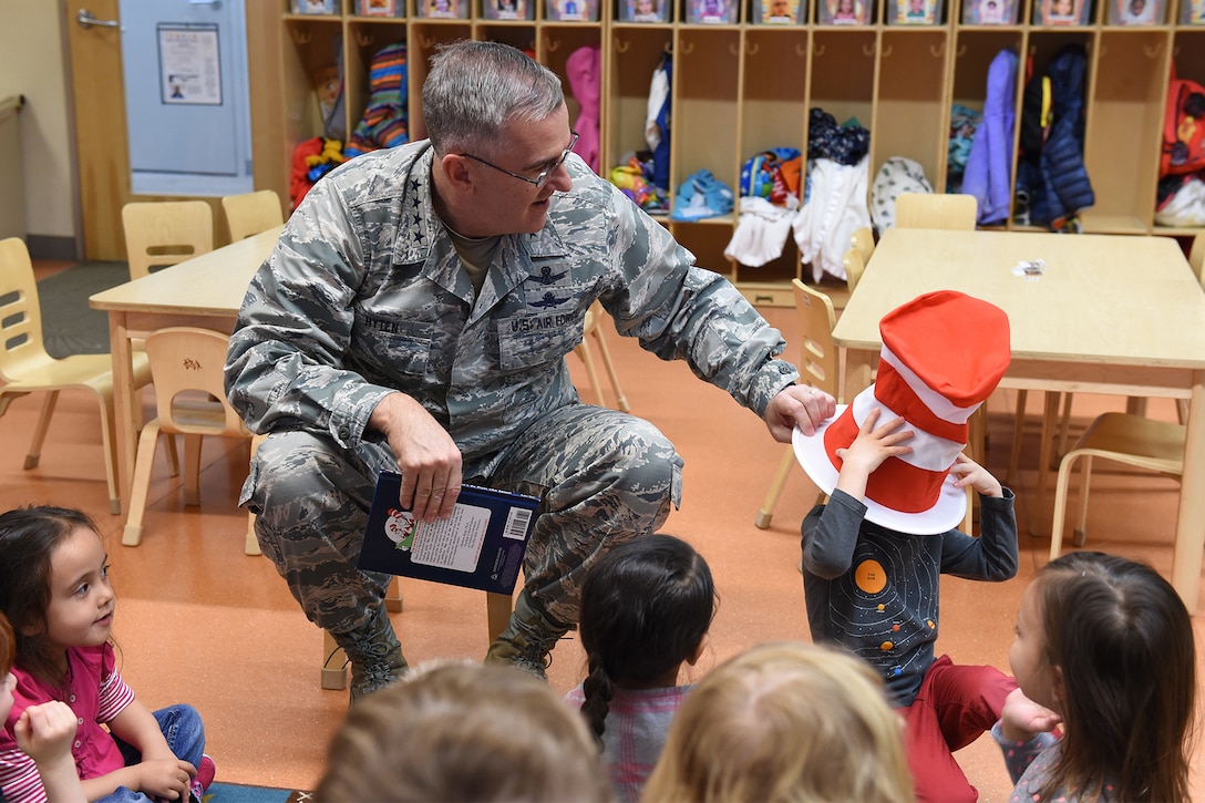 A service member puts a hat on a child.
