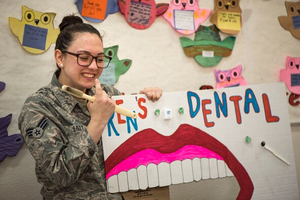 U.S. Air Force Senior Airman Courtney Lott, a 35th Dental Squadron dental technician, points to her teeth during a National Dental Health Month workshop at Misawa Air Base, Japan, Feb. 26, 2019. This event provided models for children to apply the techniques shared about proper oral hygiene. (U.S. Air Force photo by Airman 1st Class Collette Brooks)