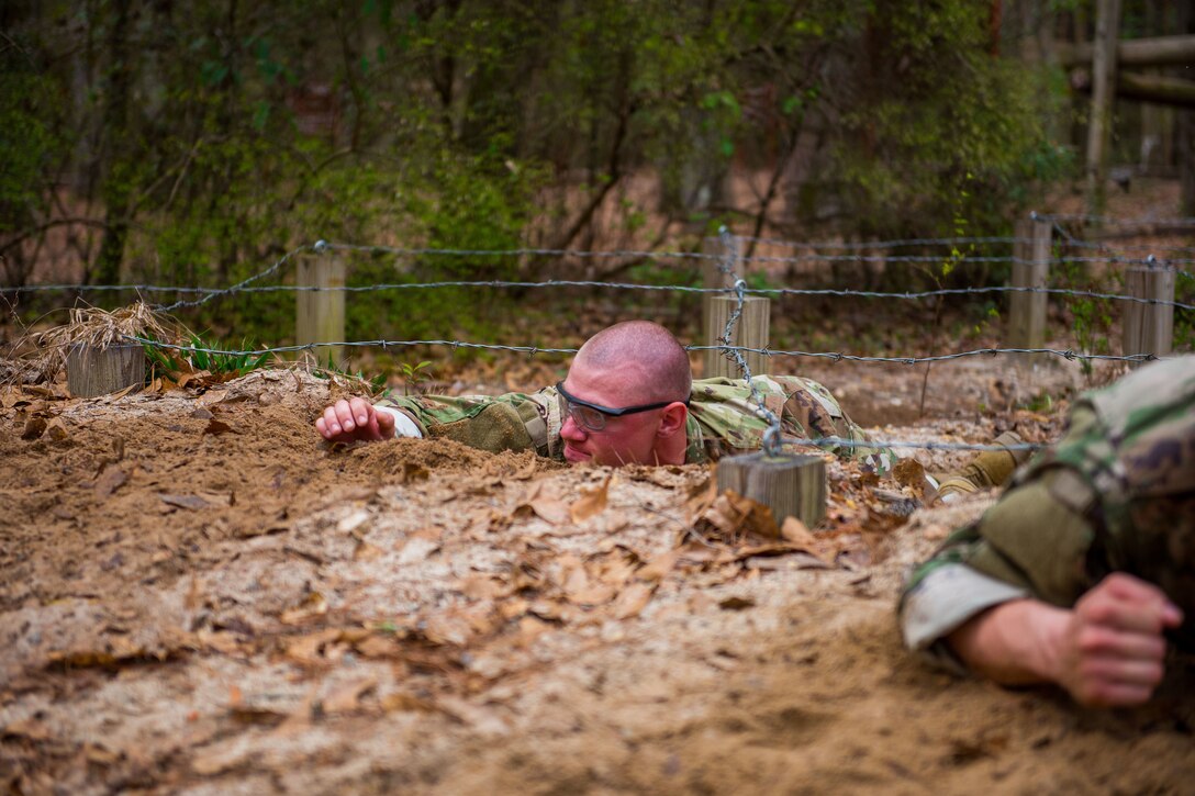 A soldier crawls through the mud during a training course.