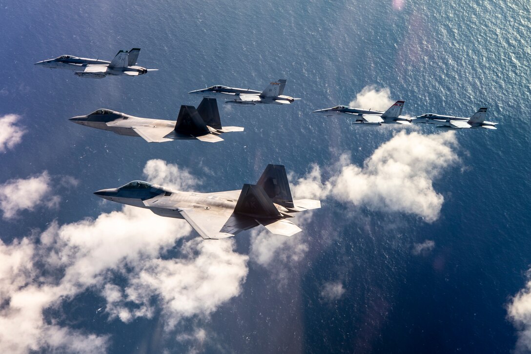 Four F/A-18 Hornets from Marine Aircraft Group (MAG) 11, 3rd Marine Aircraft Wing (MAW), fly in close formation over the Southern California coast with two F-22 Raptors from 3rd Operations Group, Elmendorf Air Force Base, Alaska, Feb. 6.  The flight commemorated joint training achieved during exercises Winter Fury 2019 and Patriot Grizzly 2019, which focused on joint large-force tactical air integration against simulated high end air-to-air and surface-to-air threats, further honing Marine and Air Force 4th and 5th generation tactics and interoperability.