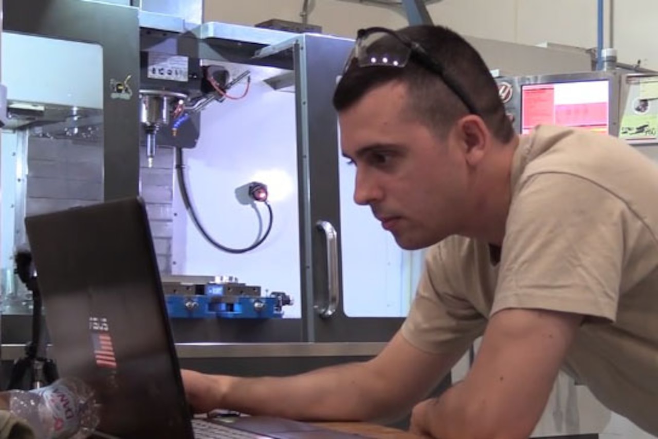 An airman sitting down working on a computer