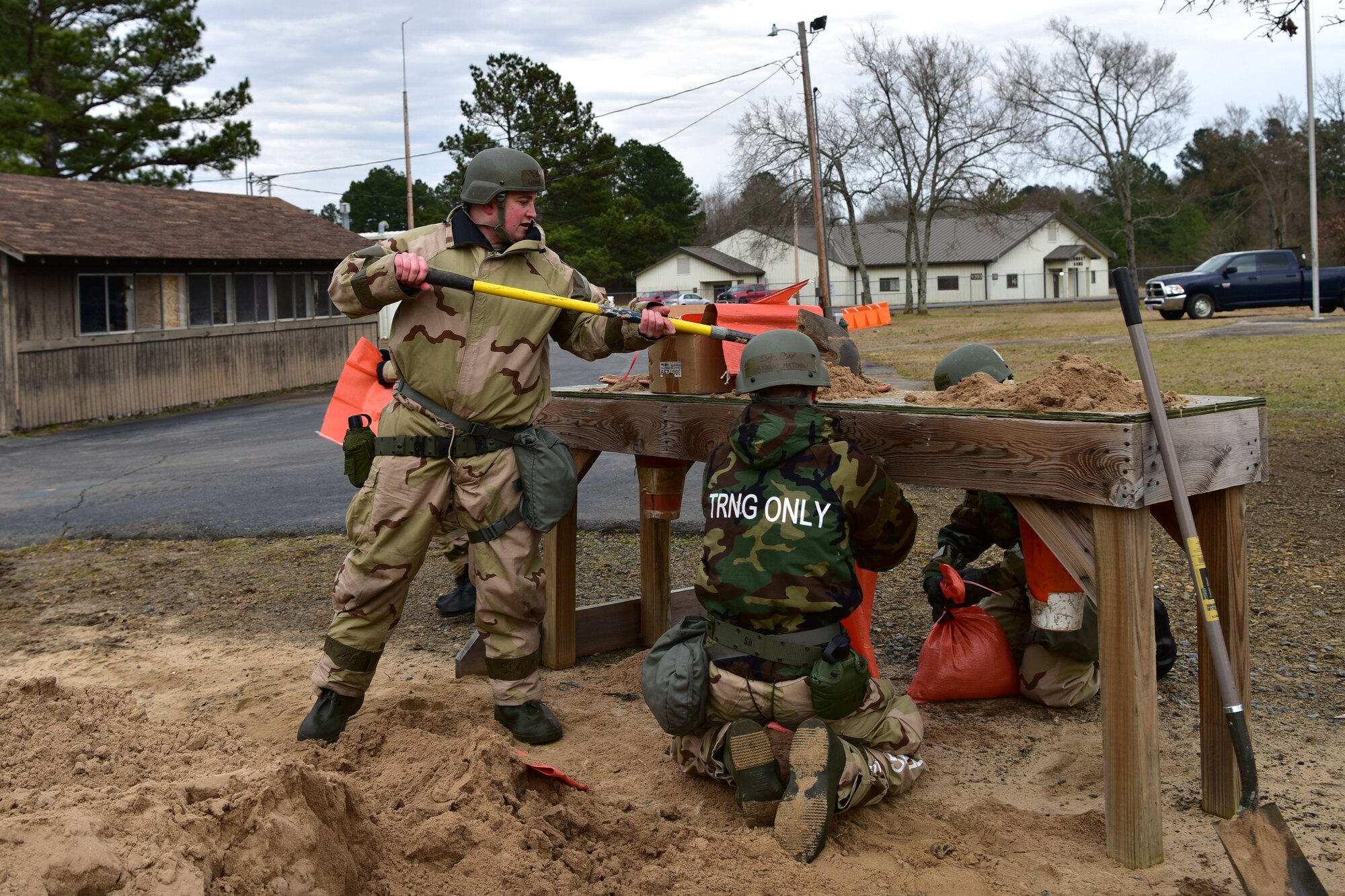 Airmen shovel sand into sandbag
