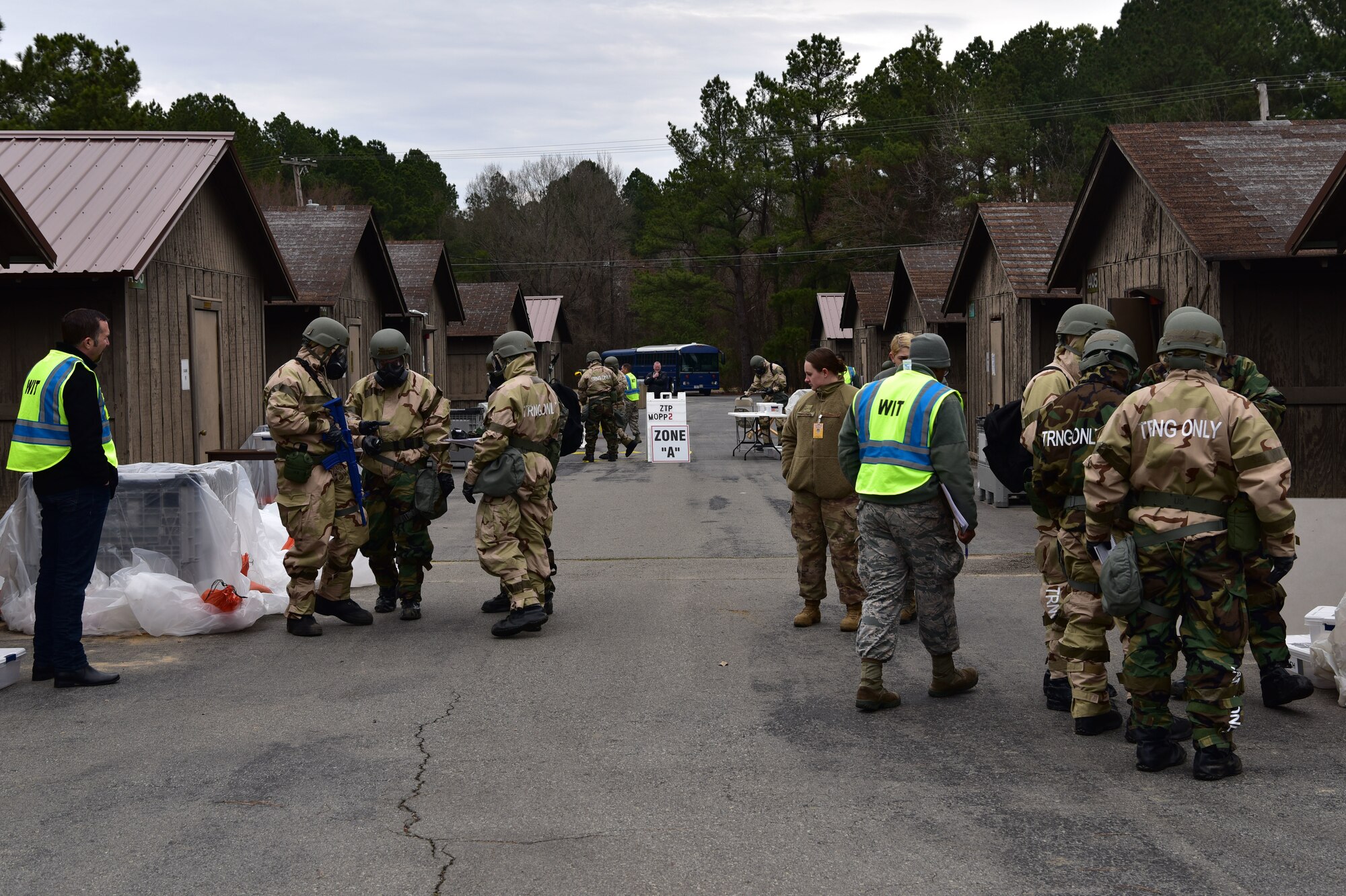 Airmen stand around in chemical protection gear