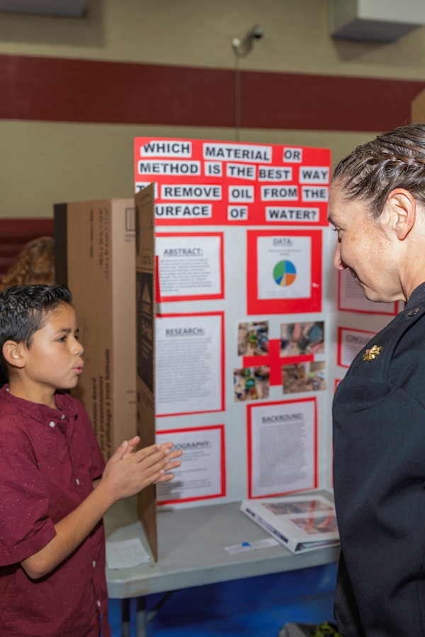 Lieutenant Commander Jamie Rivas, Public Works Officer, speaks with Drake Stewart, regarding his project on best practices of oil absorption, during the STEAM Fair at Barstow High School, Barstow, Calif., Feb. 21.
(U.S. Marine Corps Photo by Jack J. Adamyk)