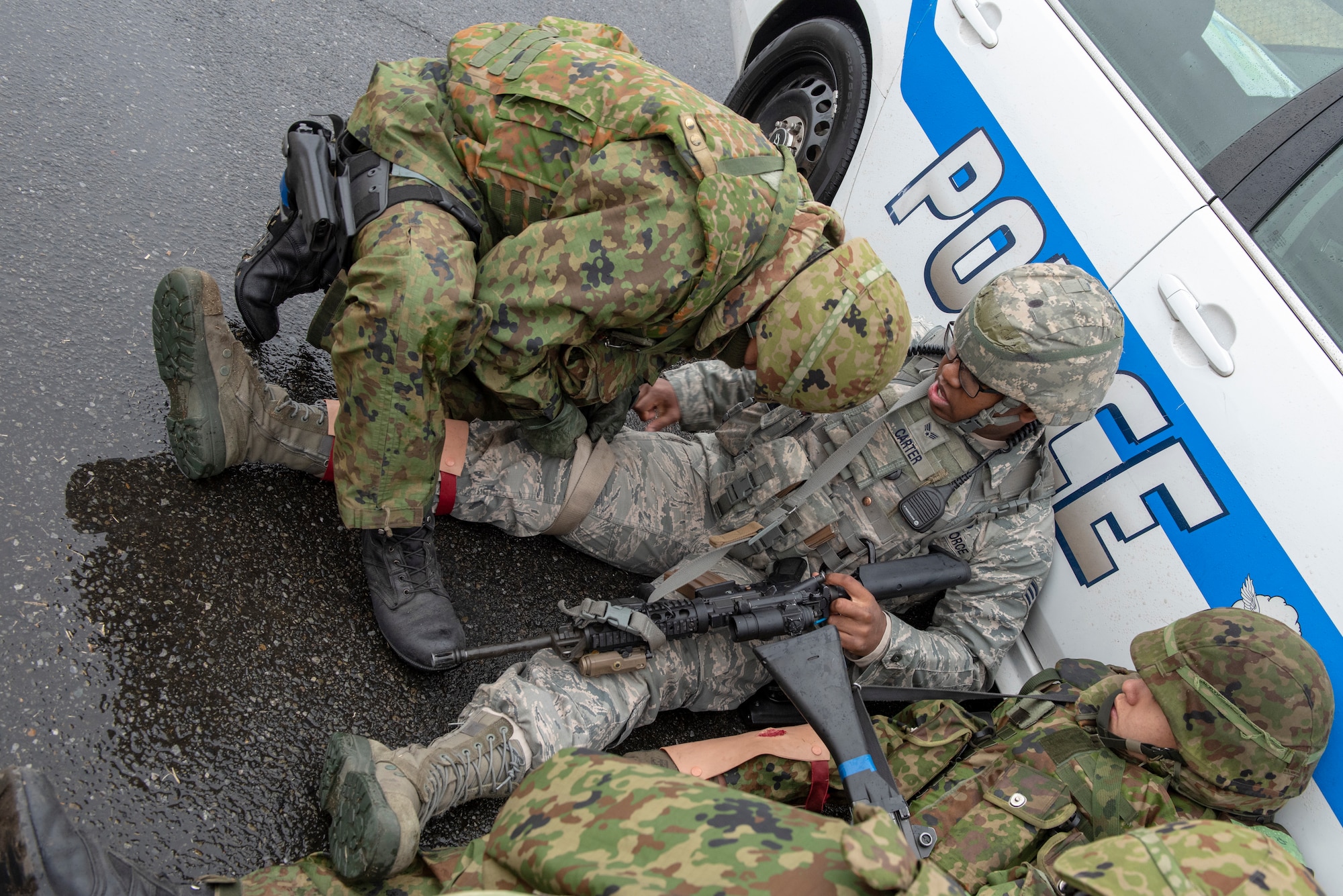 A member of the Japan Ground Self-Defense Force (JGSDF) 34th Infantry Regiment out of Camp Itazuma in Gotemba, Japan applies a tourniquet to an Airman with the 374th Security Forces Squadron with a simulated leg injury during Guard and Protect 2019 at Yokota Air Base, Japan, Feb. 28, 2019.